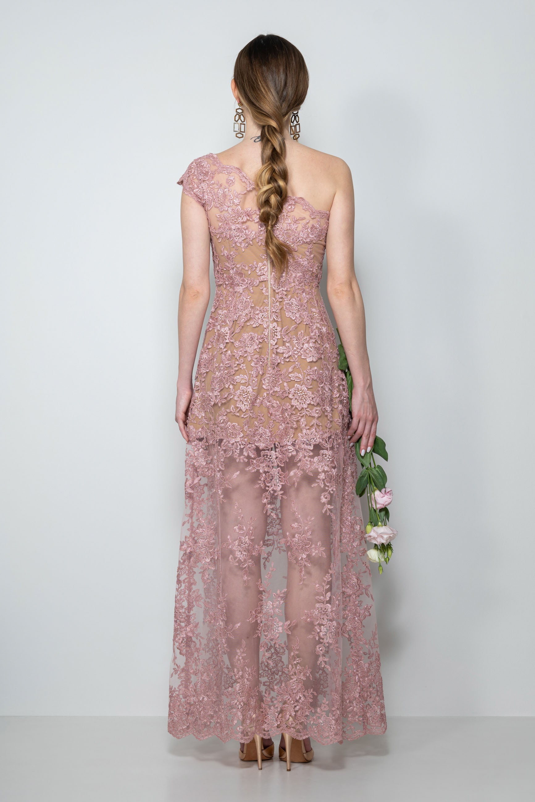 Abito cerimonia in pizzo rebrodè rosa antico “Charlotte” indossato da modella, con dettaglio dello scollo asimmetrico e ricami.