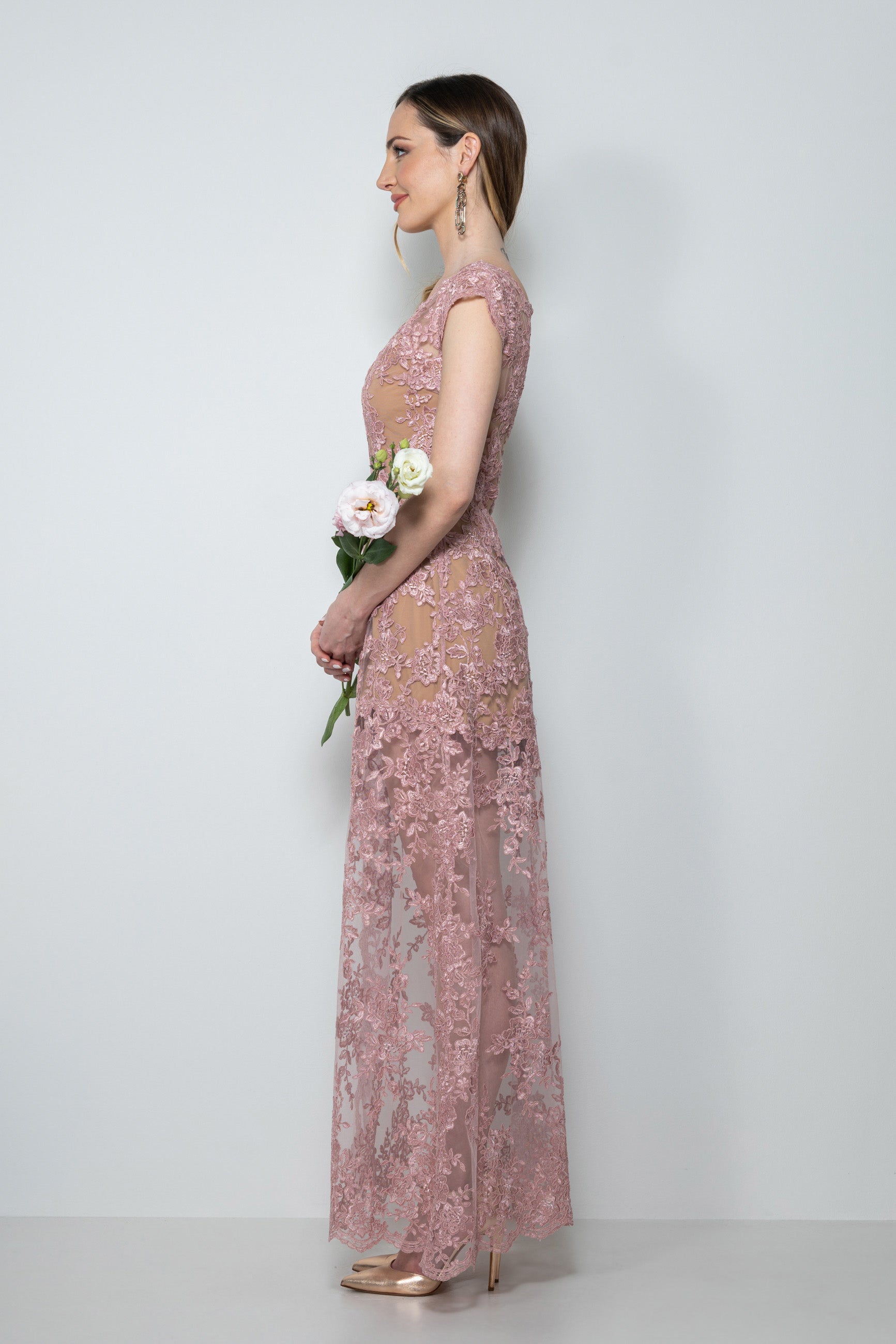 Abito cerimonia in pizzo rebrodè rosa antico “Charlotte” indossato da modella, con dettaglio dello scollo asimmetrico e ricami.