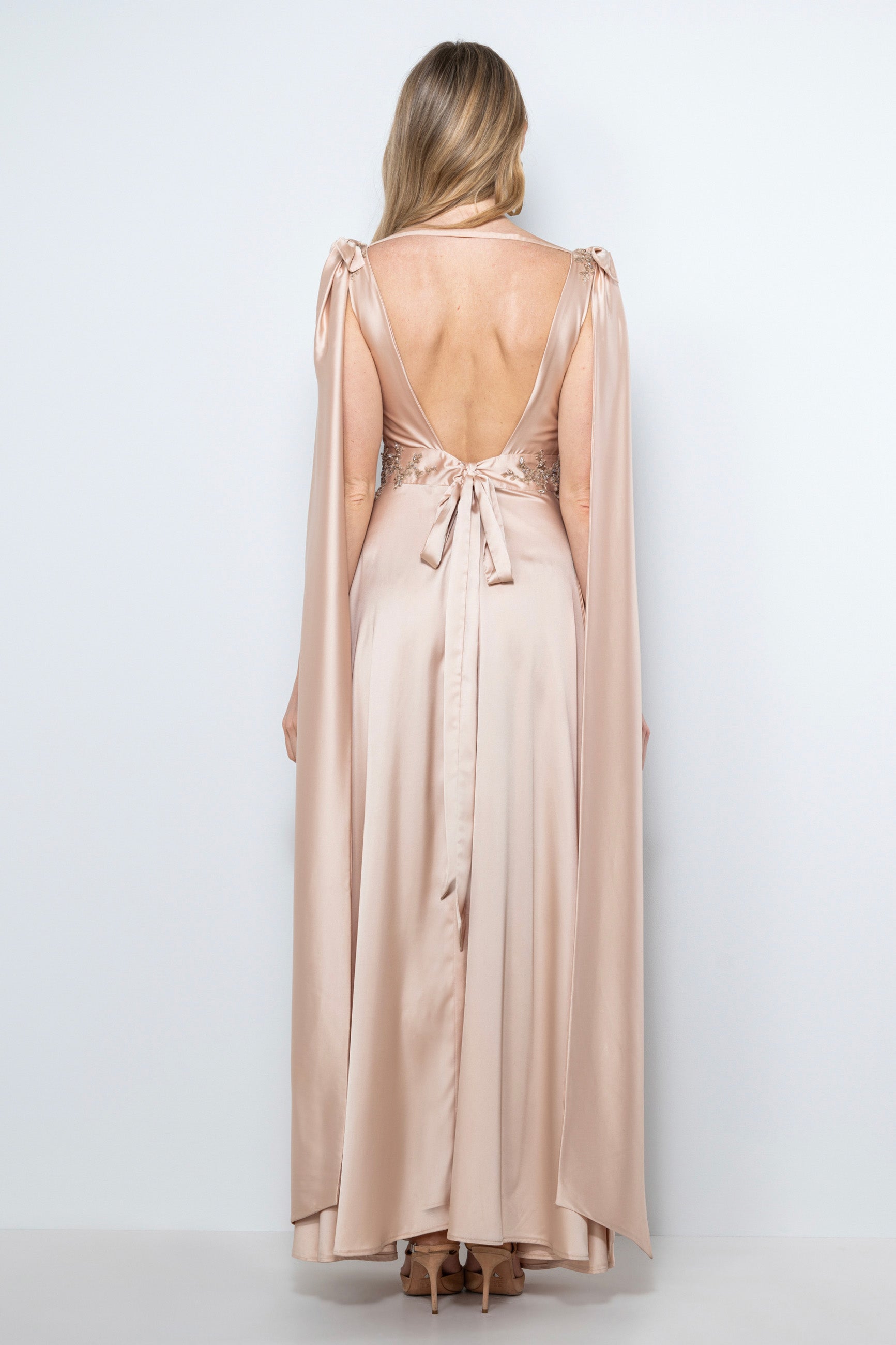 abito cerimonia lungo in satin color cipria con fiocchi staccabili e ricami fatti a mano, indossato da modella.