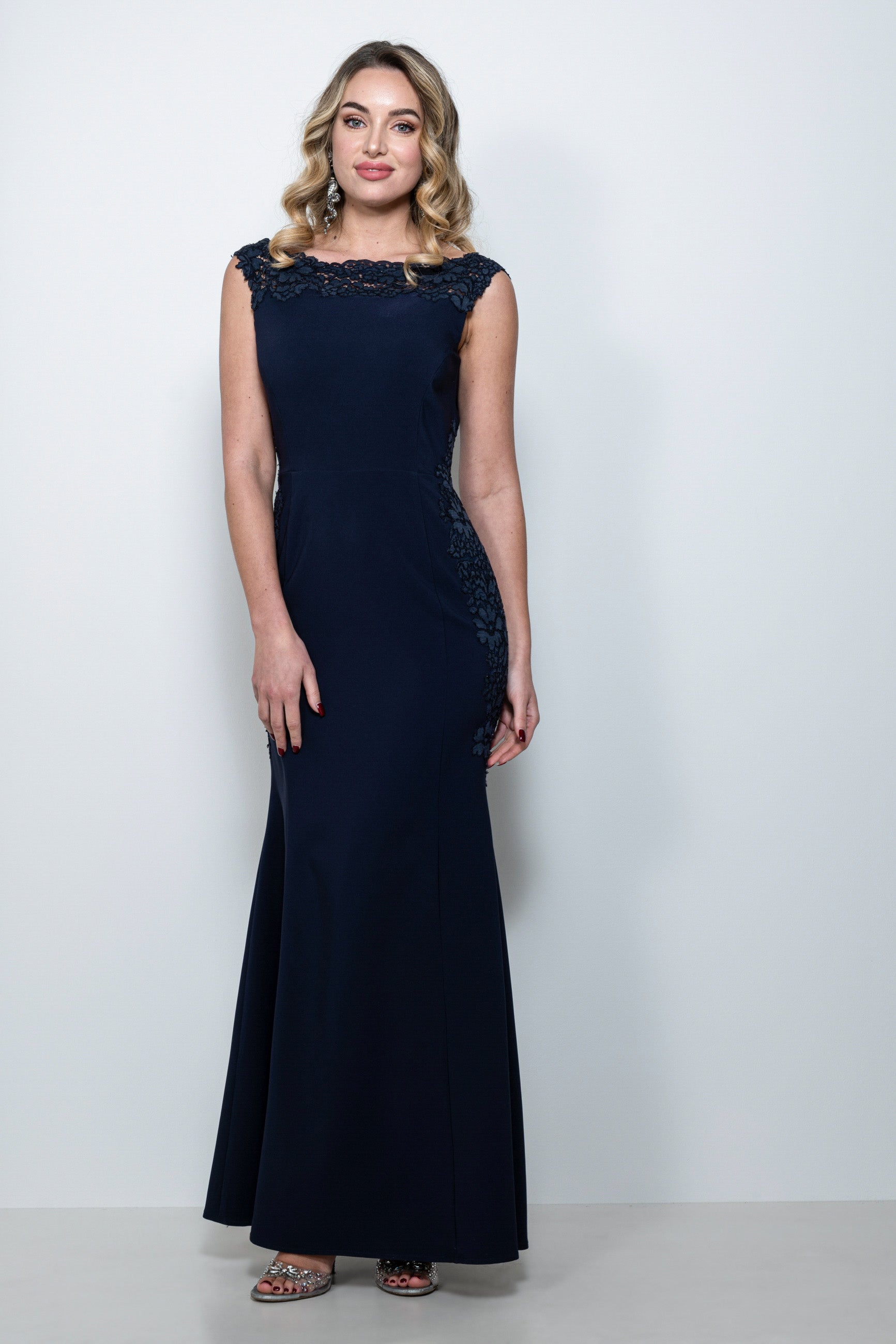 Abito cerimonia in pizzo blu “Dafne” indossato da modella, con dettagli in pizzo smerlato e manica staccabile.