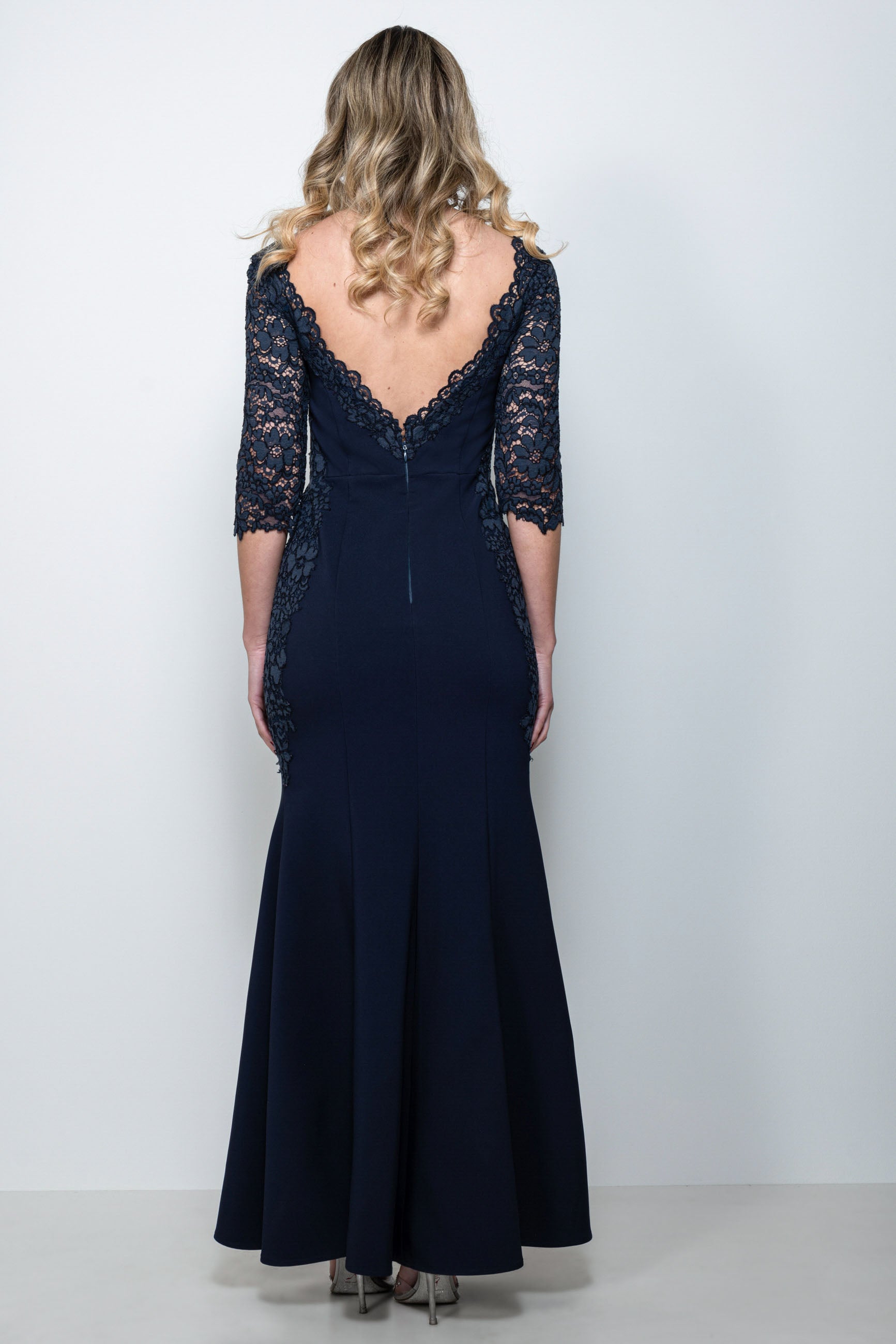 Abito cerimonia in pizzo blu “Dafne” indossato da modella, con dettagli in pizzo smerlato e manica staccabile.