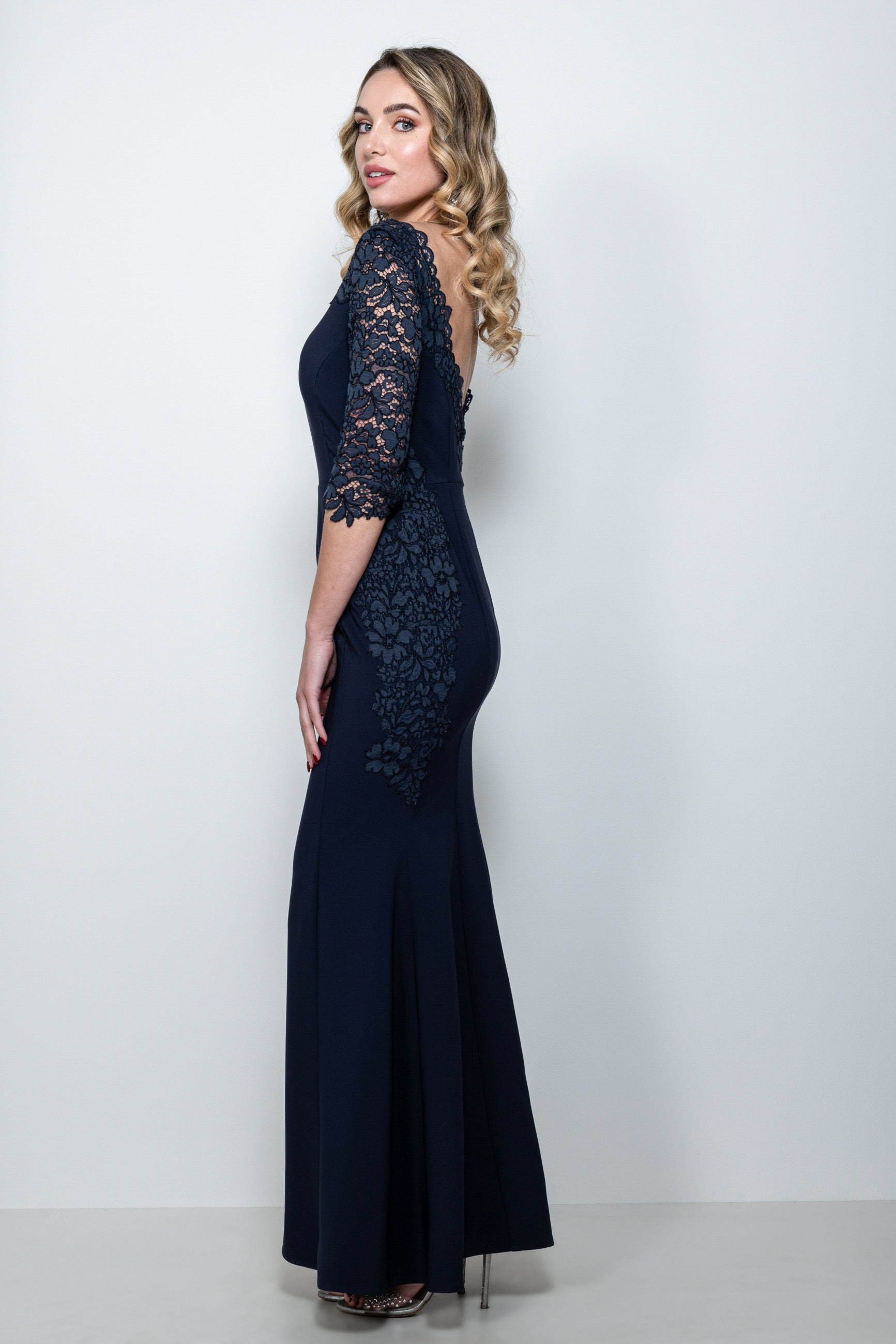 Abito cerimonia in pizzo blu “Dafne” indossato da modella, con dettagli in pizzo smerlato e manica staccabile.